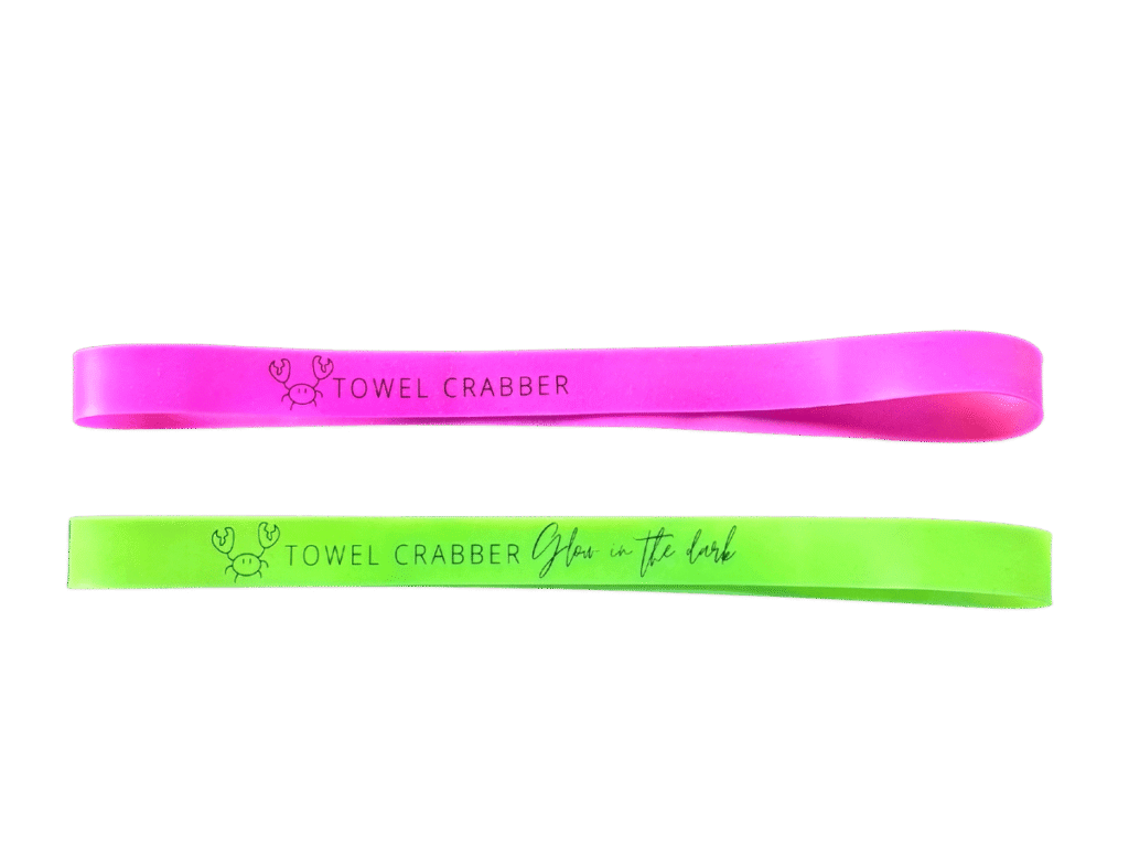 Pink and lime green silicone Towel Crabber bands featuring a small crab graphic and text, with the green band reading "Glow in the dark".
