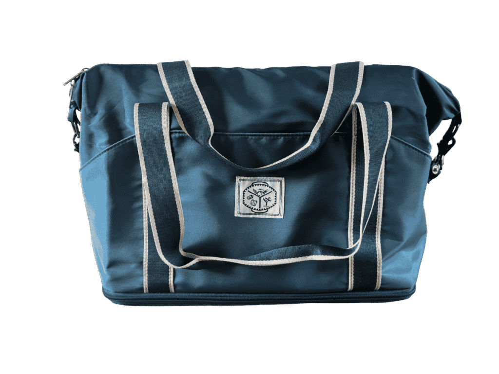 Dark blue expandable travel tote bag with light-colored webbed straps and a front brand patch against a transparent background.